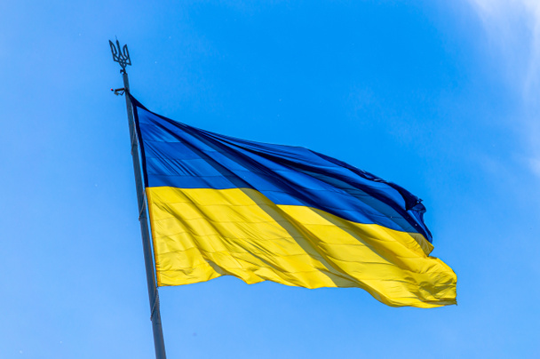 На блакитному небі летить великий національний прапор України. - Фото, зображення