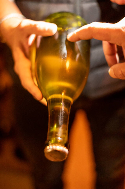Comprobación de levadura en botellas, producción de vino espumoso de champán en botellas en bastidores en bodega subterránea oscura, Reims, Champagne, Francia - Foto, Imagen