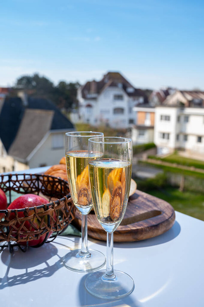 Выпивка шампанского Brut игристого вина в бокалах для флейты на открытой террасе кафе или бистро во Франции в солнечный день - Фото, изображение