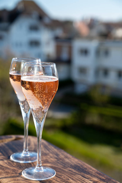 Pití šumivého vína z růžového šampaňského z flétnových sklenic na venkovní terase ve Francii za slunečného dne - Fotografie, Obrázek