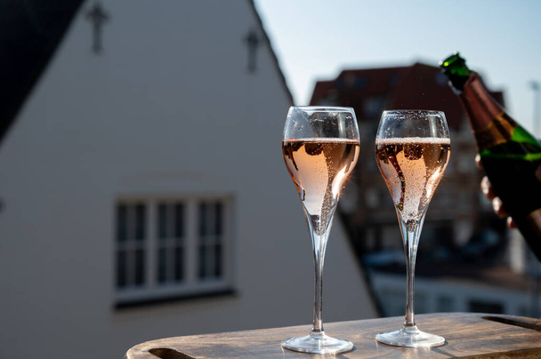 Пиття трояндового шампанського ігристе вино з склянок флейти на терасі у Франції в сонячний день. - Фото, зображення