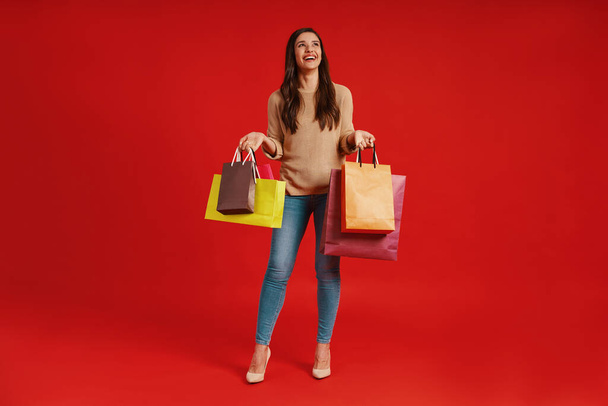 Full length of beautiful young woman in casual clothing carrying shopping bags and smiling - Foto, Imagem