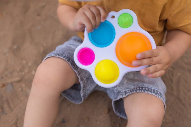 colorful trendy antistress sensory toy fidget push pop it and simple dimple in kids hands, children share toys and playing together. - Foto, immagini