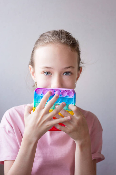 Teenager Mädchen spielen mit runden Silikon bunte Anti-Stress-Pop-it-Spielzeug. Drücken Sie Pop Bubble in die Hände. Nahaufnahme. - Foto, Bild