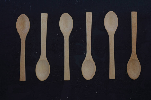 empty wooden spoons on a black background, top view, set - Foto, imagen
