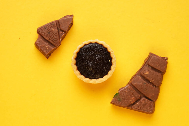 Una foto di 4 crostata al cioccolato e bar su sfondo giallo. Cibo preparato per dessert. - Foto, immagini