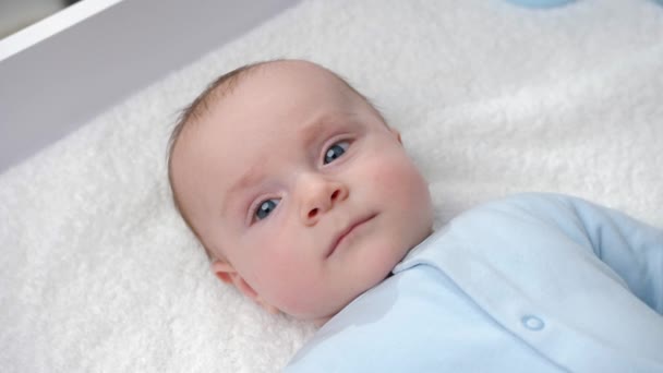 Portrait de bébé garçon souriant heureux avec les yeux bleus souriant sur la coiffeuse. Concept d'hygiène, de soins pour bébés et de santé - Séquence, vidéo