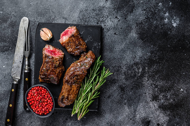 Grilled brisket steaks in bbq sauce on a marble board. Black background. Top view. Copy space - Фото, зображення