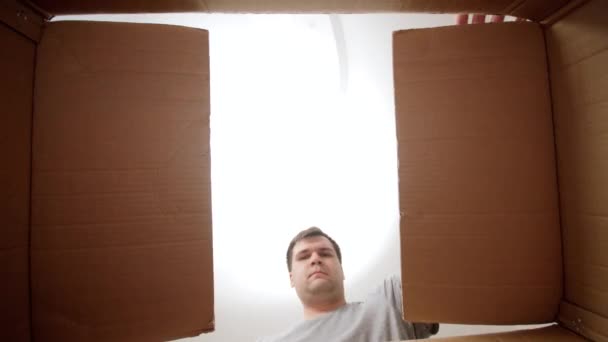 Ein junger Mann öffnet einen Karton und staunt. Überraschung im Paket - Filmmaterial, Video