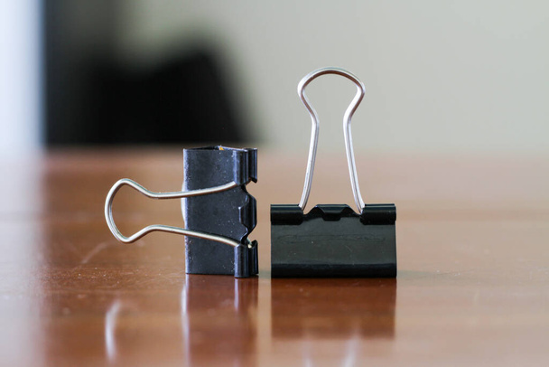 a pair of black binder clips as office tools in document administration - 写真・画像