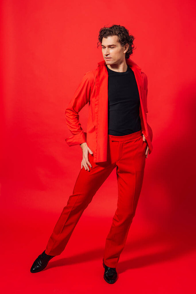 Portrait of a tall handsome man dressed in red shirt posing on the red background. - Photo, image