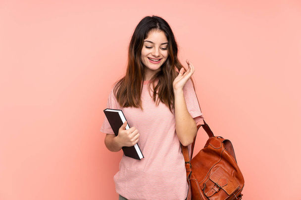 Молодая студентка собирается в университет на изолированном розовом фоне смеясь - Фото, изображение