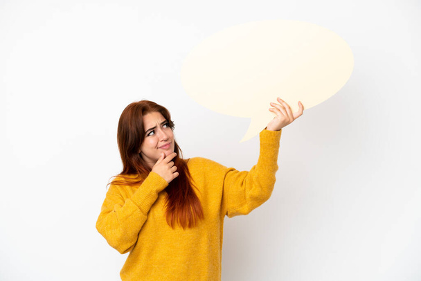 Jeune rousse femme isolée sur fond blanc tenant une bulle de discours vide et pensant - Photo, image