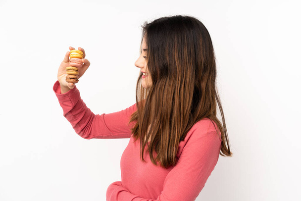 Young caucasian woman isolated on pink background holding colorful French macarons and happy - Фото, зображення