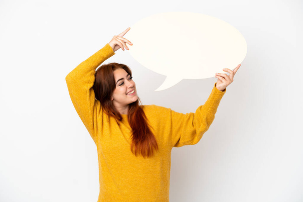 Young redhead woman isolated on white background holding an empty speech bubble - Photo, Image
