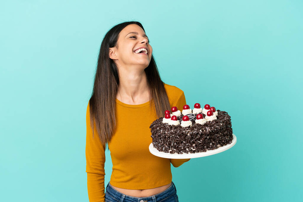 Young caucasian woman holding birthday cake isolated on blue background laughing - Foto, immagini