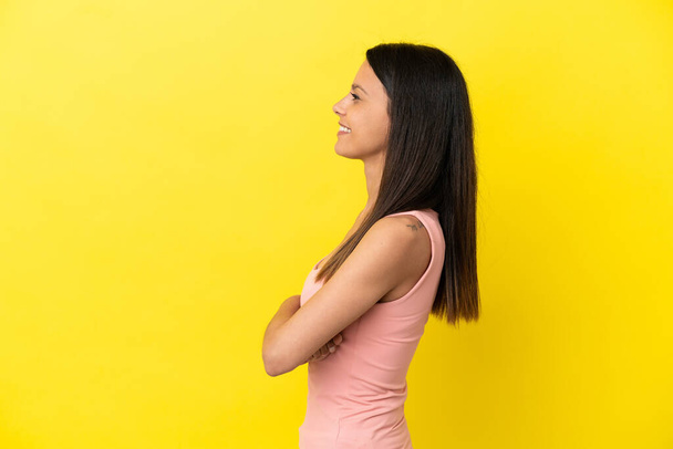 Mujer joven caucásica aislada sobre fondo amarillo en posición lateral - Foto, Imagen