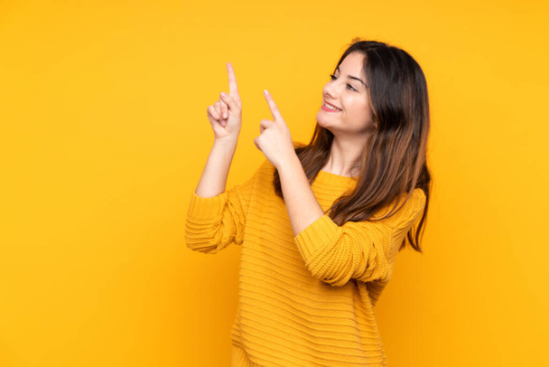Young caucasian woman isolated on yellow background pointing with the index finger a great idea - Foto, Imagem