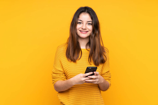 黄色の背景に隔離された若い白人女性携帯電話でメッセージを送る - 写真・画像