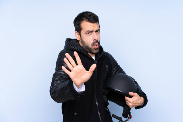 Man with a motorcycle helmet over isolated background nervous stretching hands to the front - Foto, Imagen