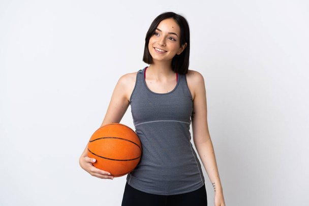 Mujer joven jugando al baloncesto aislada sobre fondo blanco pensando en una idea mientras mira hacia arriba - Foto, imagen