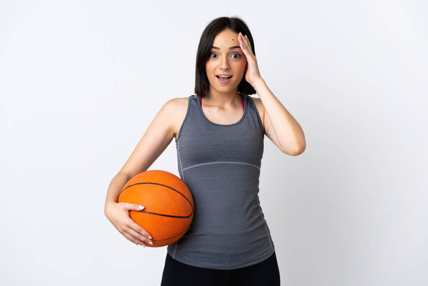 Basketbol oynayan genç bir kadın sürpriz bir ifadeyle beyaz arka planda izole edilmiş. - Fotoğraf, Görsel