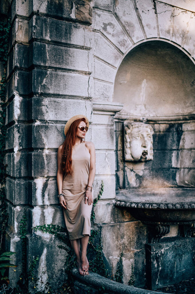 Young sensual woman tourist in sunglasses summer dress stands barefooted on ancient palace balcony balustrade, parapet  - Foto, Imagem