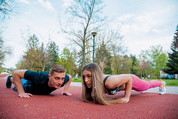 Colpo di sana giovane coppia facendo esercizi di stretching insieme sul prato verde al mattino - Foto, immagini