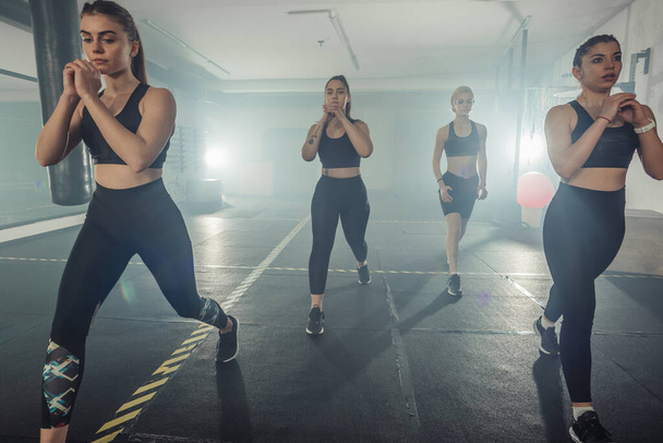 Gruppo di sportivi in abbigliamento sportivo che fanno esercizio fisico in palestra con la gamba destra - Foto, immagini