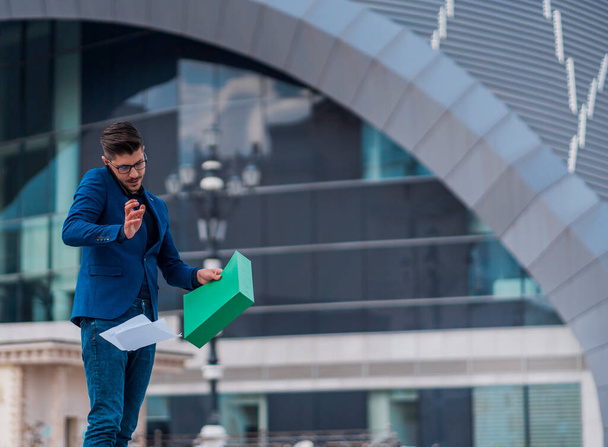 Moderne zakenman met groene map praten op mobiele telefoon in stedelijke plaats - Foto, afbeelding