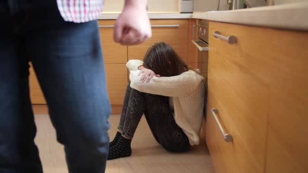 Boze vader met gebalde vuist die wegloopt van huilende dochter die op de keukenvloer zit. Begrip huiselijk geweld en gezinsagressie. - Video