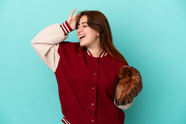 junge rothaarige Frau spielt Baseball isoliert auf blauem Hintergrund und lächelt viel - Foto, Bild