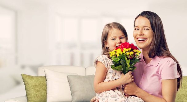 Little child congratulating mom with Mothers day at home and giving her fresh flower bouquet. - Photo, image