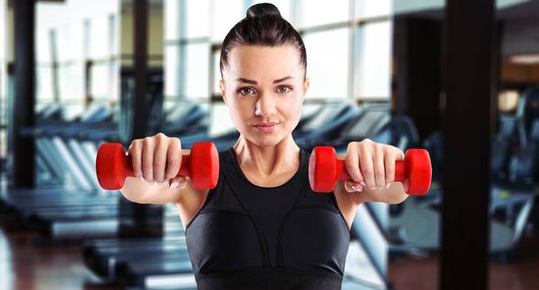 Womans hand holding a dumbbell on gym background. - Foto, Bild