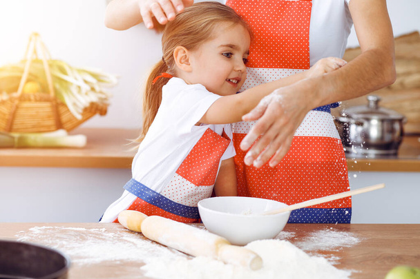 Happy woman and her daughter are kneading the dough and baking cookies for a delicious family feasting in sunny kitchen. Christmas, New year, Thanksgiving, Anniversary, Mothers Day. Healthy meal cooking concept. - Foto, Imagem