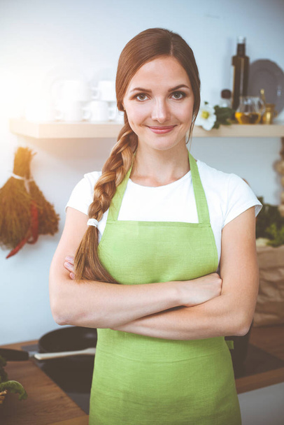 An attractive young woman ready to cook a new recipe for a delicious salad mix while standing in sunny kitchen. - Foto, Bild