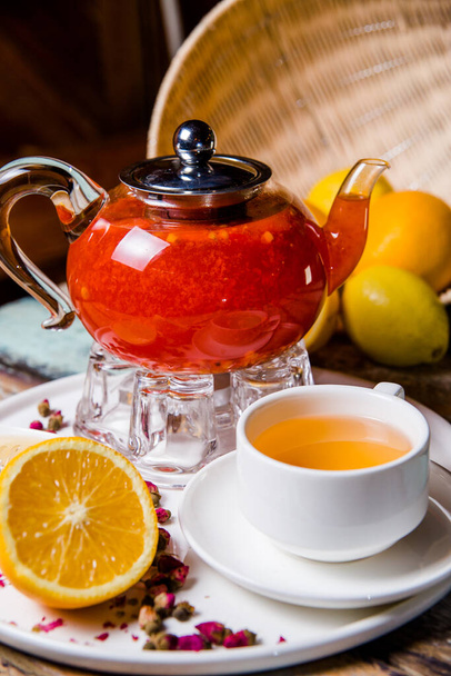 a cup of buckthorn tea in a glass teapot on the table - Fotó, kép
