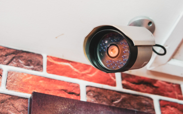 Close-up view of the front of the CCTV camera with clear lens mounted on the wall for security. - Photo, Image