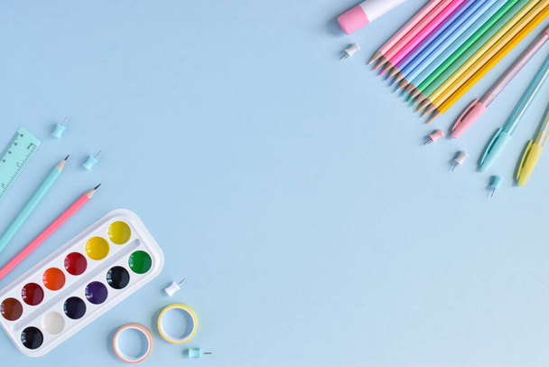 A frame of school supplies in pastel colors on a light blue background, space for text. Office supplies. Back to school. Flat lay. - 写真・画像