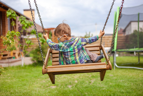 Child swinging on a swing in the backyard - Fotoğraf, Görsel