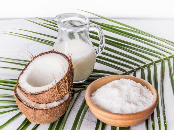 coconut milk with coconut shavings and broken coconut on palm leaf. - Photo, Image