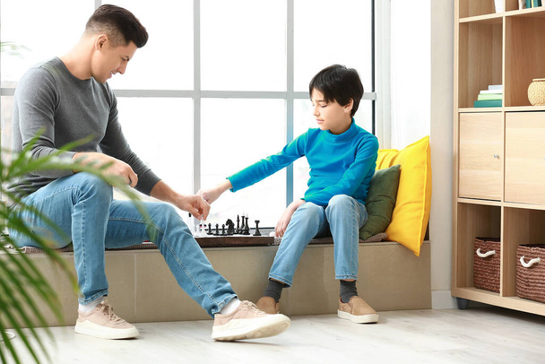 Батько і син грають в шахи вдома
 - Фото, зображення