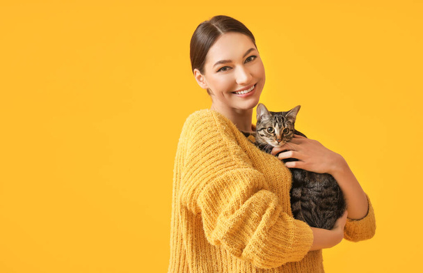 Schöne junge Frau mit niedlicher Katze auf farbigem Hintergrund - Foto, Bild