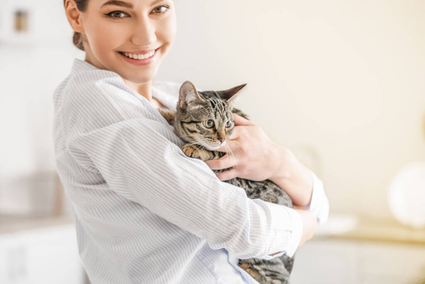 Beautiful young woman with cute cat in kitchen - Foto, imagen