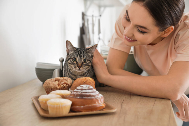 Beautiful young woman with cute cat in kitchen - Фото, зображення