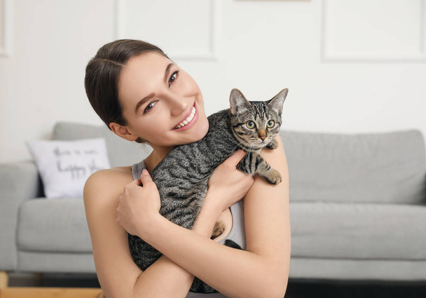 Beautiful young woman with cute cat at home - Fotó, kép