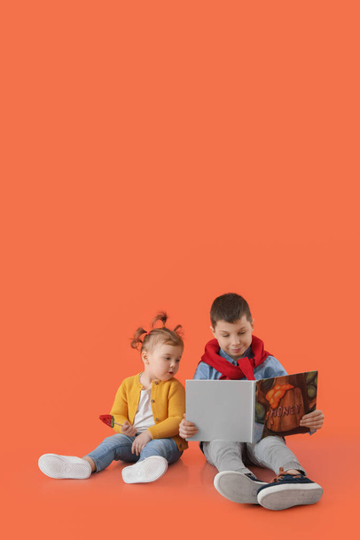 Schattige kleine kinderen met boek over kleur achtergrond - Foto, afbeelding
