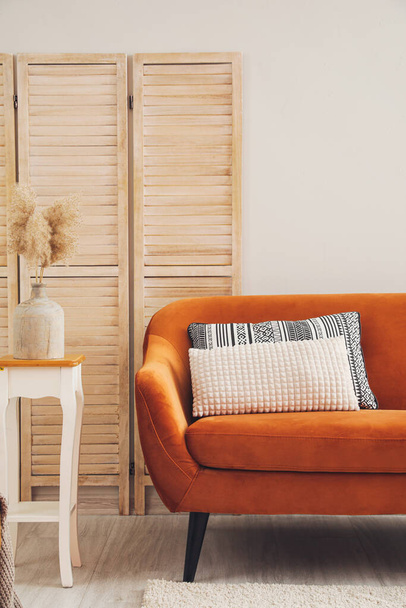 Sofá elegante com mesa e tela dobrável perto da parede clara - Foto, Imagem