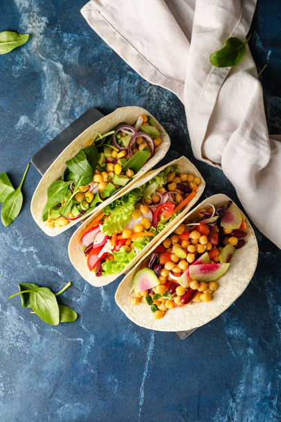 Stand con sabrosos tacos vegetarianos sobre fondo de color - Foto, imagen