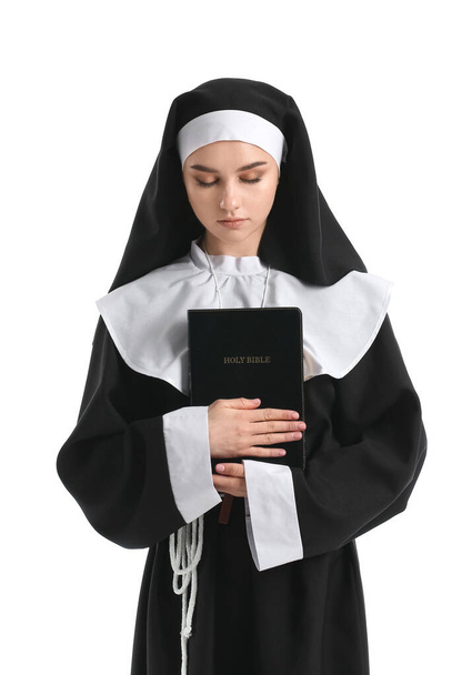 Young praying nun with Bible on white background - Photo, Image